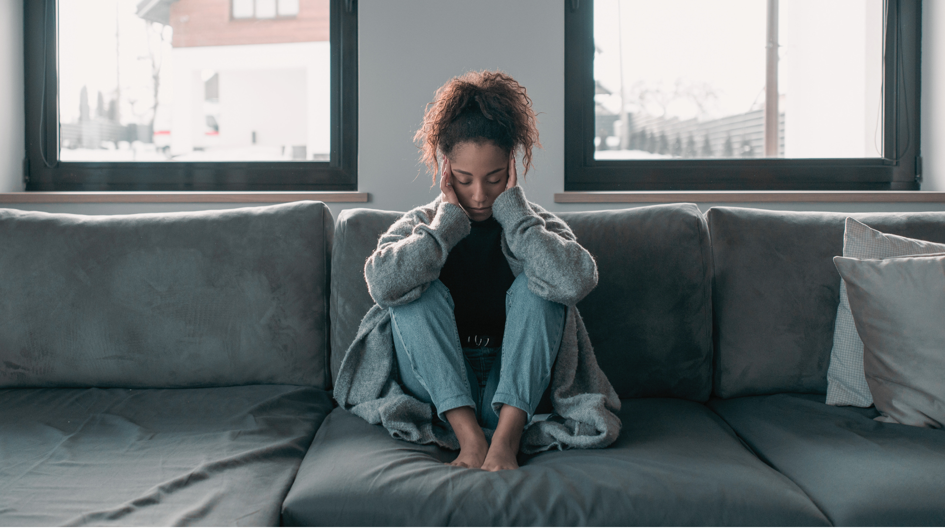 woman on couch with head in hands