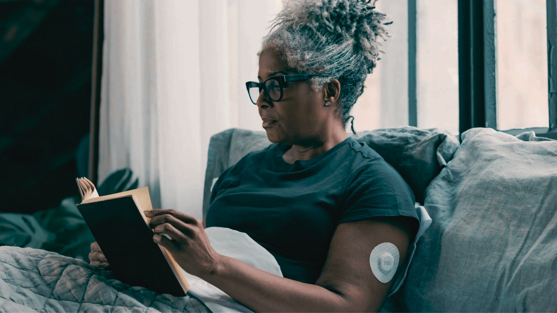Middle-aged woman sitting on a couch reading a book